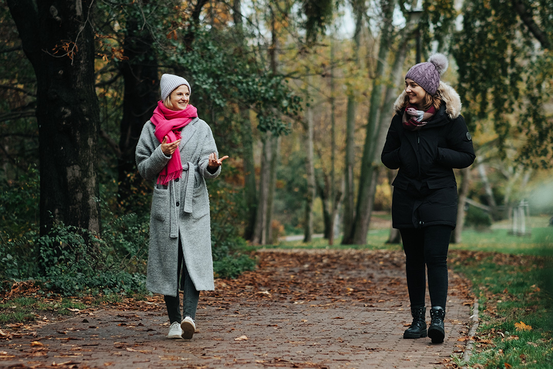 Zwei Nachbarinnen unterhalten sich bei einem gemeinsamen Spaziergang im Park